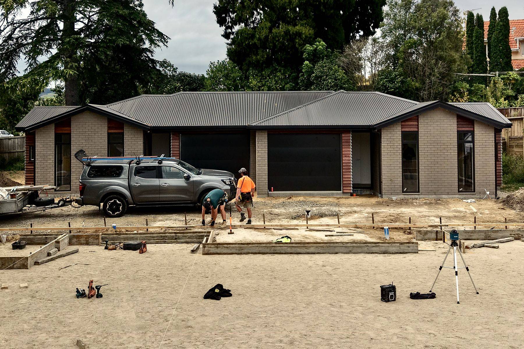 TAG crew setting out foundations beside a completed brick home